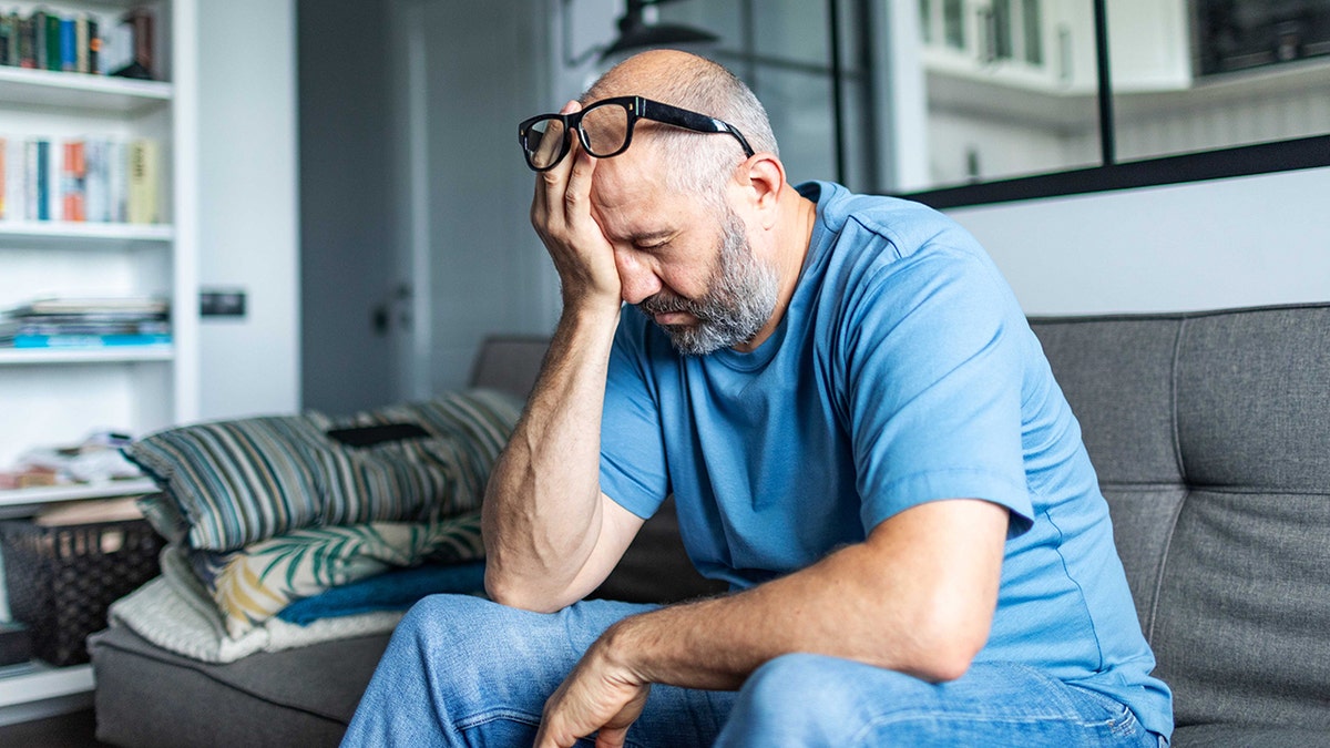 tired, fatigued man sitting on sofa