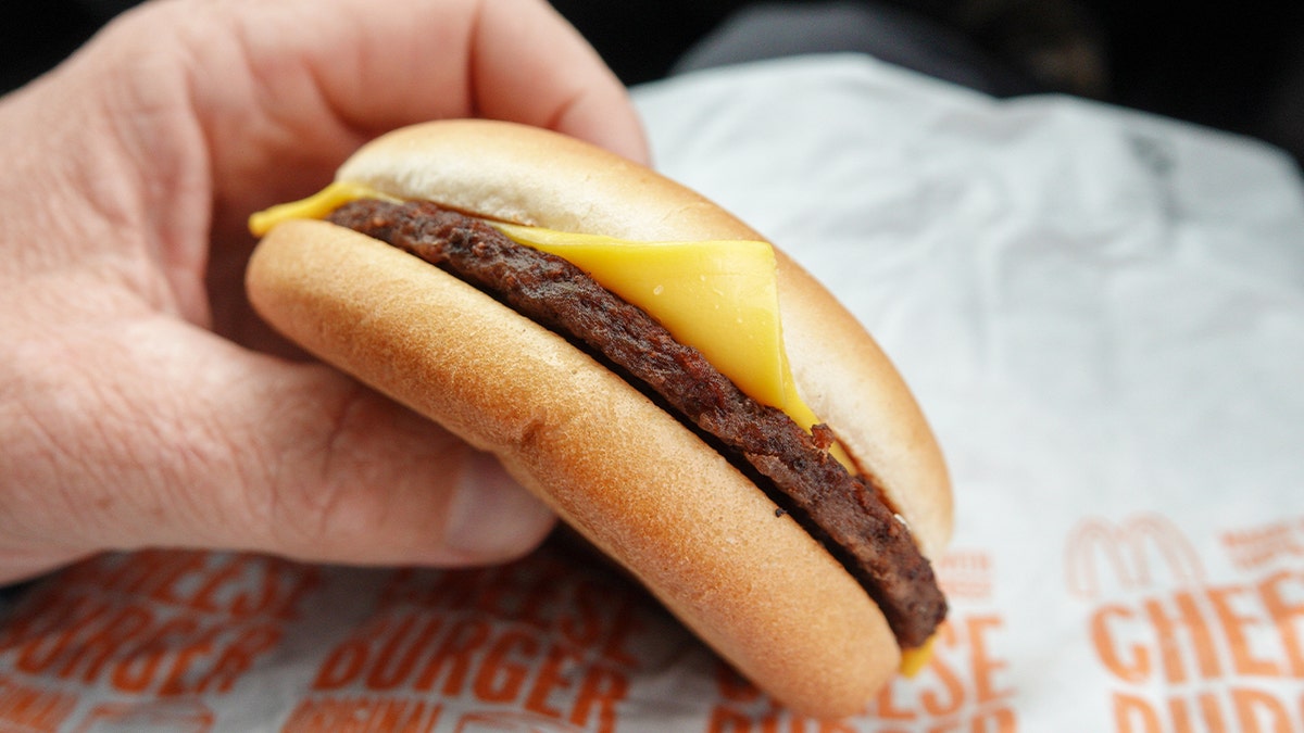 Man holding McDonald's cheeseburger