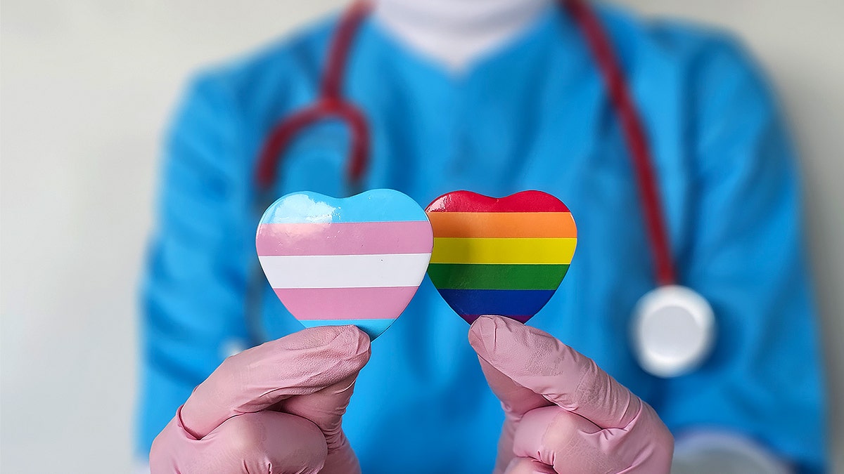 Doctor holding LGBT rainbow and transgender pins.