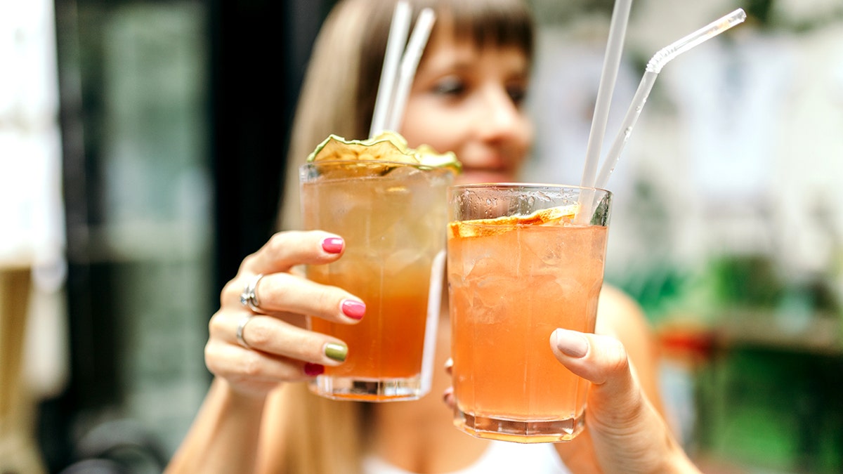 Two young women sitting in cafe bar drinking cocktails