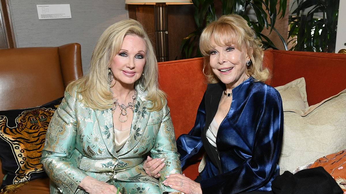 Morgan Fairchild在Barbara Eden旁邊穿淺綠色西裝，並穿著藍色的污漬外套和白色上衣。