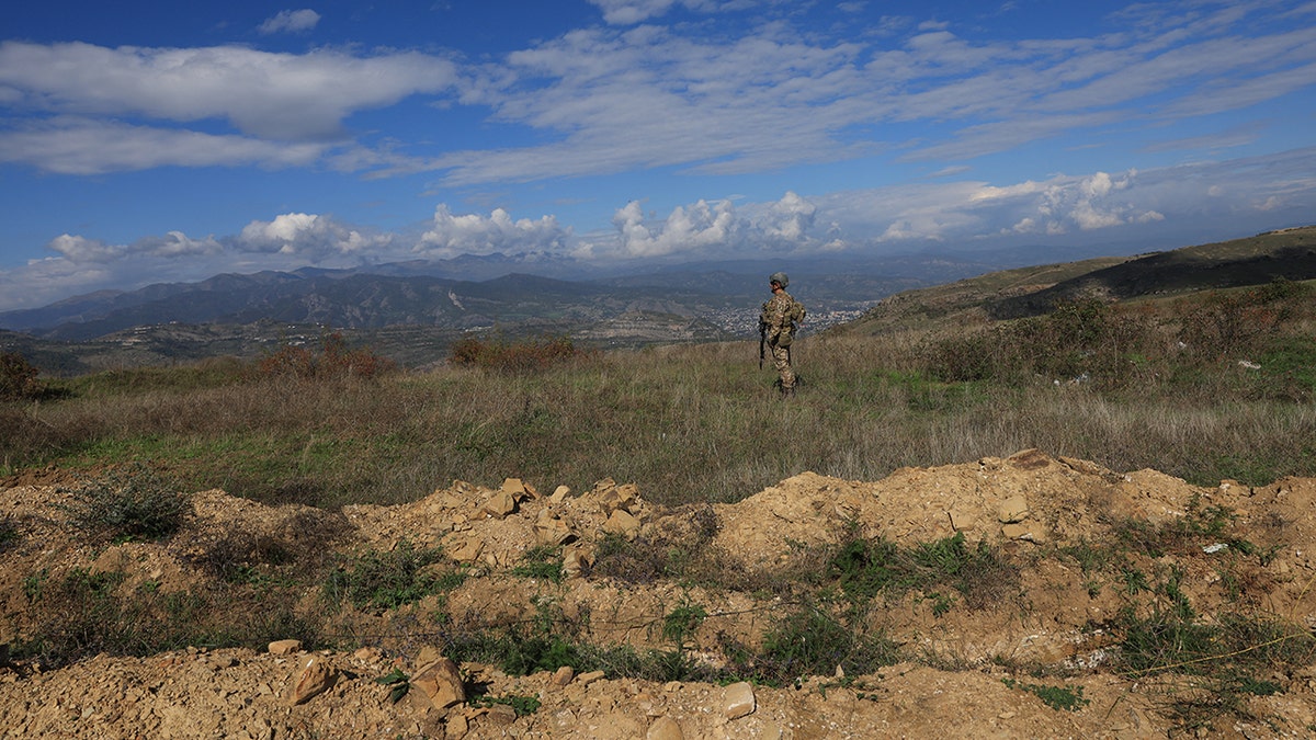 An Azeri serviceman stands near trenches at a former Armenian separatists military position in the village of Mukhtar (Muxtar) retaken recently by Azeri troops, during an Azeri government-organized media trip, in Azerbaijan's controlled region of Nagorno-Karabakh, on Oct. 3, 2023.