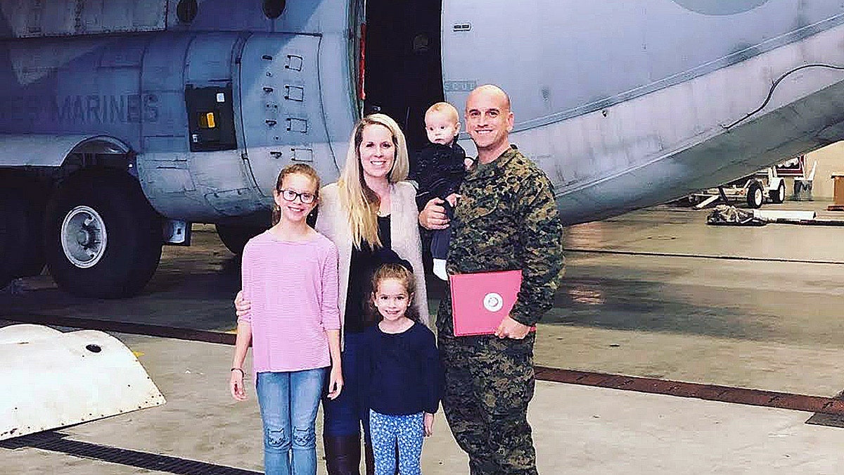 Marine Master Sgt. Jon Ogasian with wife Sarah and children at military airfield.