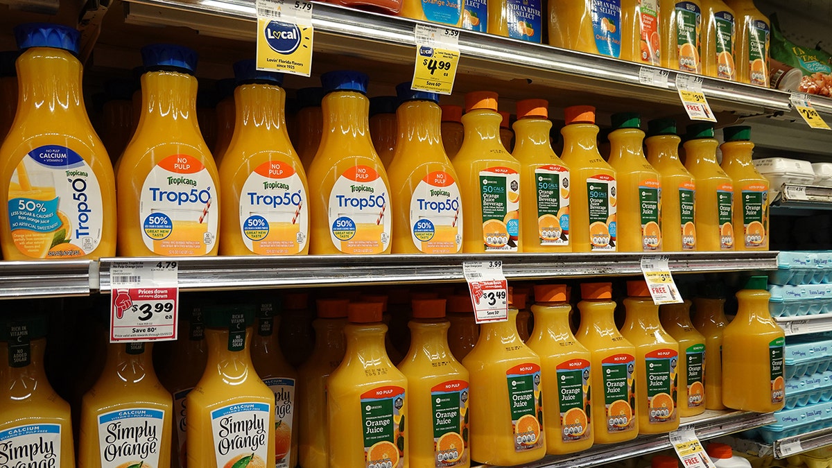 Orange juice variety seen on fridge shelves in supermarket with discount and price stickers