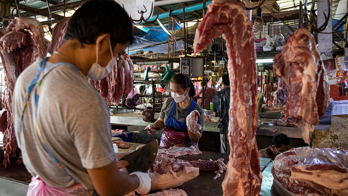 Butcher sees cutting pork in Thailand, meat hovering in the market