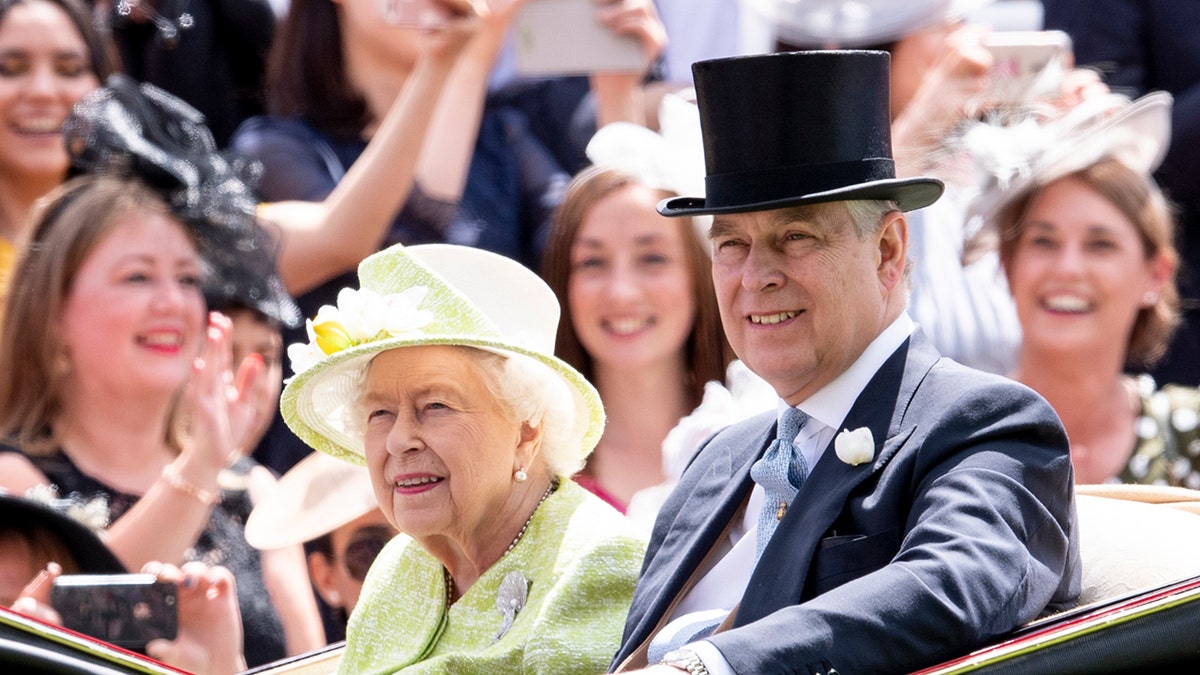 Queen Elizabeth wearing a yellow dress and matching hat sitting next to Prince Andrew in a dark suit and top hat on a royal carriage.