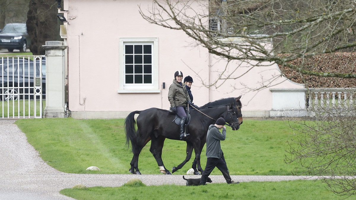 Prince Andrew riding on a horse near Royal Lodge with other people looking on.