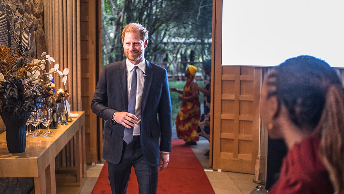 Princis Harijs staigā uzvalkā, turot kaklasaiti.