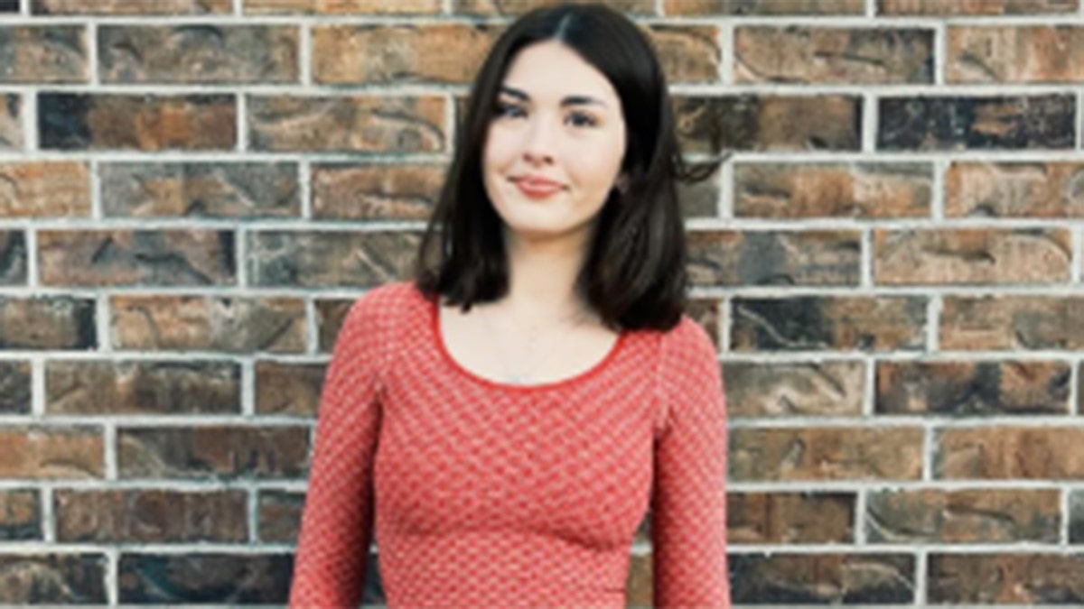 Priscilla Robertson poses in front of a brick wall.