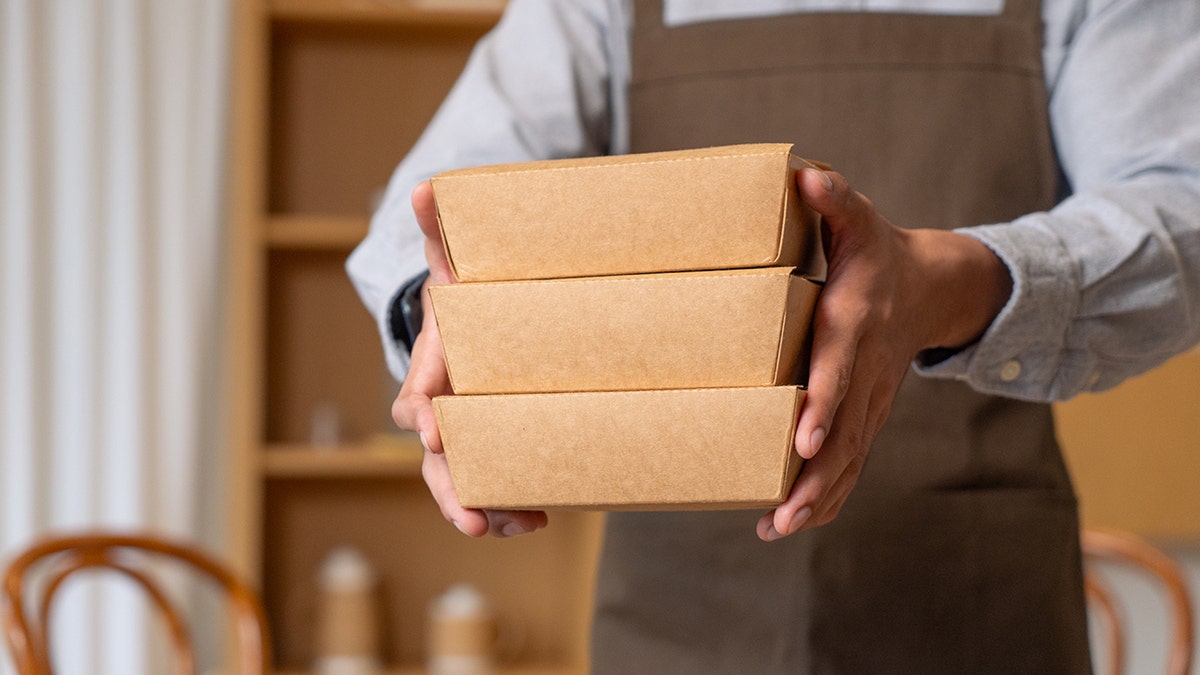 Waiter holding three to-go boxes