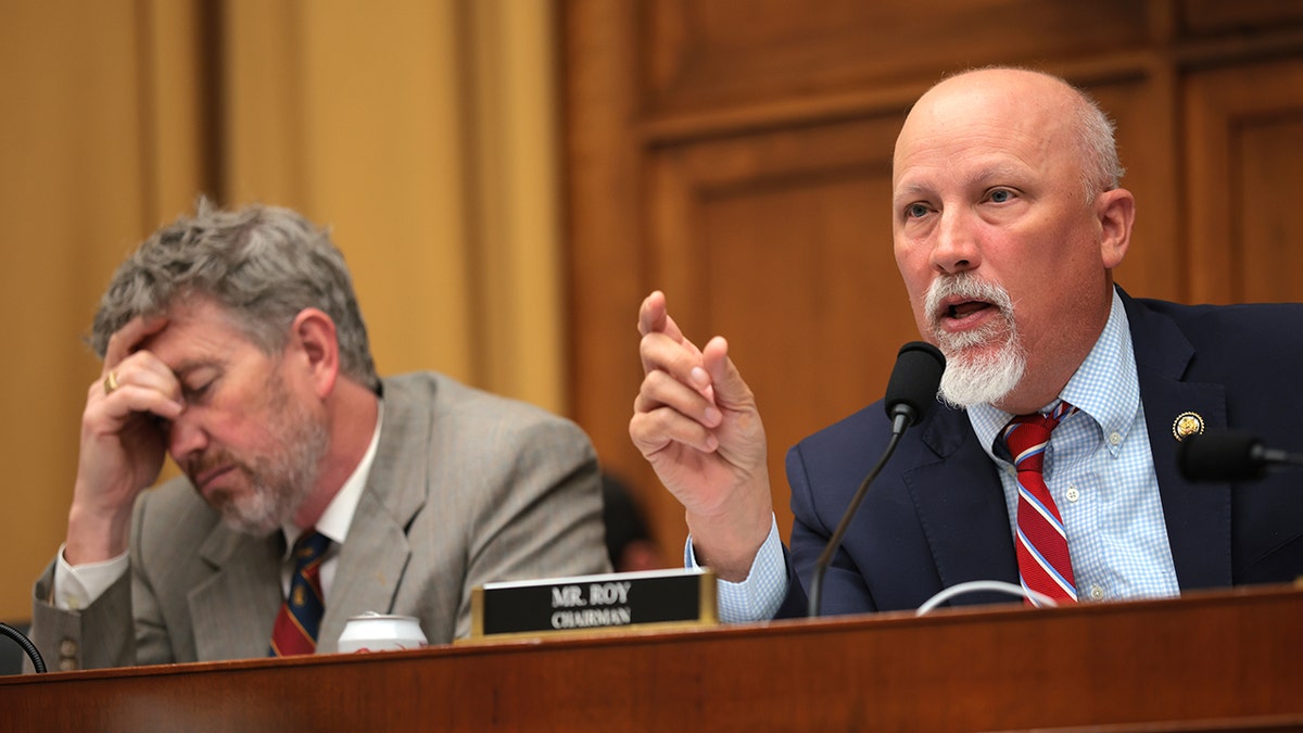 Chip Roy speaks while sitting next to Thomas Massie during a committee hearing