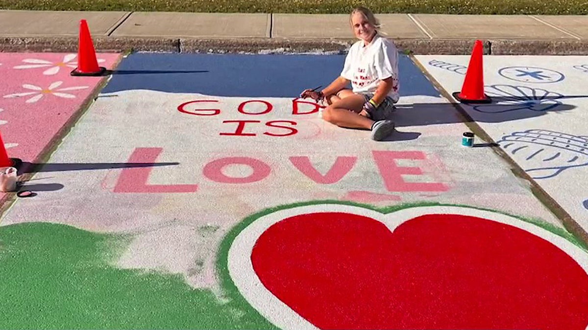 Sabrina Steffans, a New York teen, poses with the religious artwork on her school parking space
