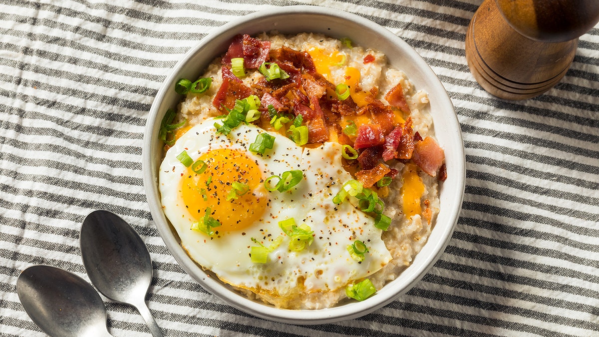Savory oatmeal topped with runny eggs, bacon and green onions.