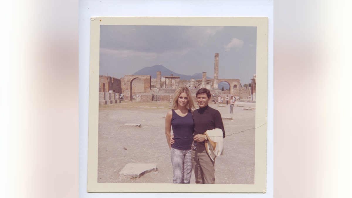 Sharon Tate and Jay Sebring outside leaning against each other smiling while on vacation.