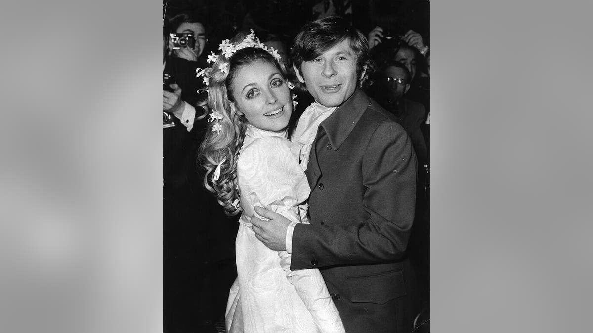 Sharon Tate in her wedding dress being held by Roman Polanski.