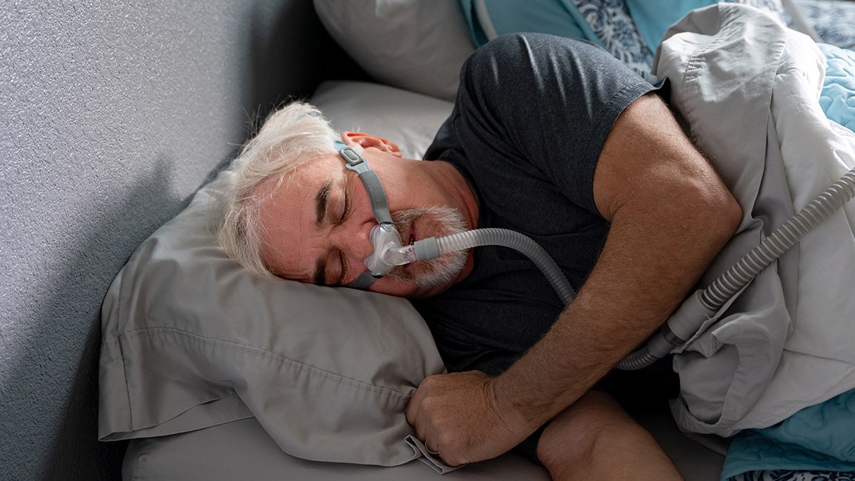 Man sleeps with the CPAP machine for sleep apnea