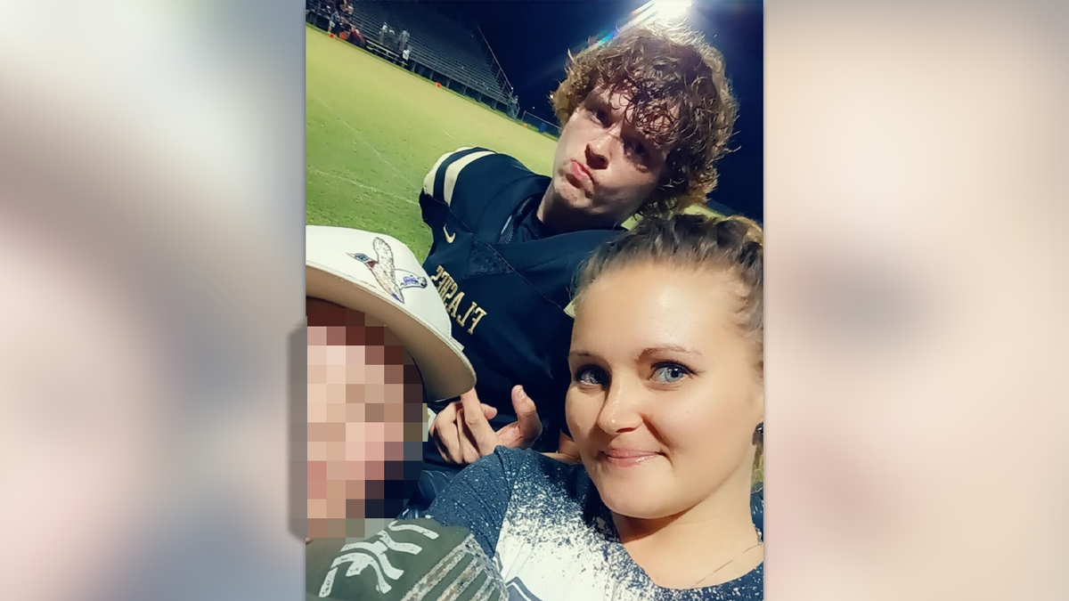 Trey Wright in a black and gold football uniform on the field, surrounded by his mom and little brother in a group selfie