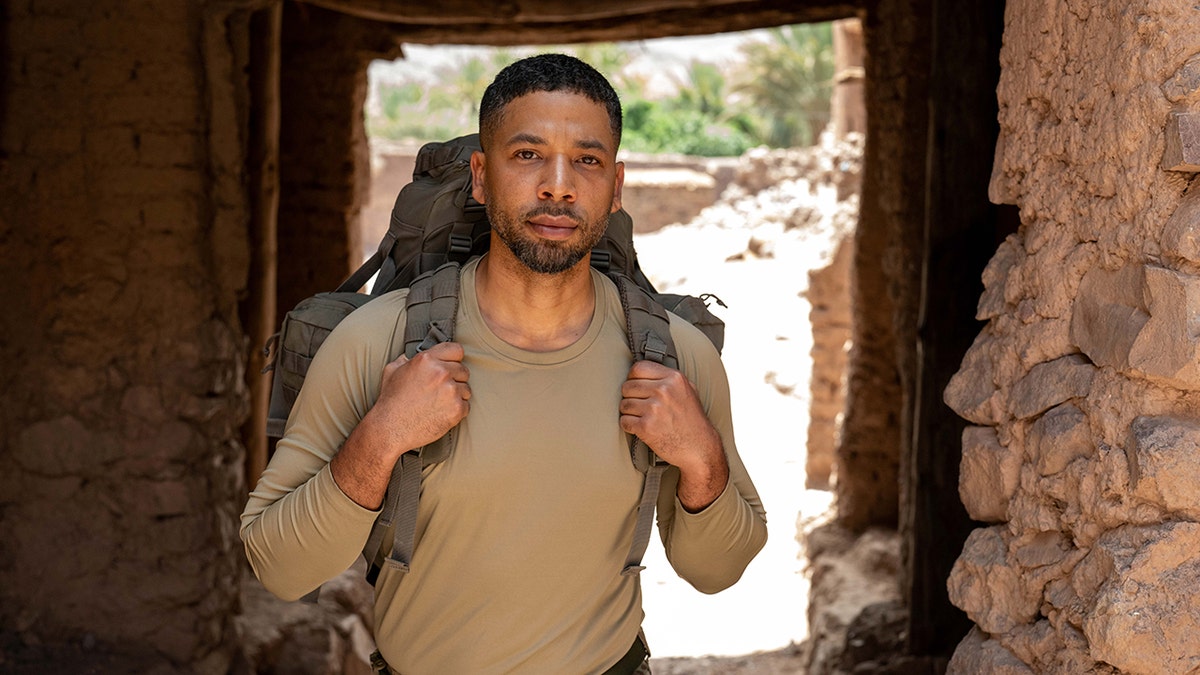 Jussie Smollett穿著綠色襯衫，並穿著背包。