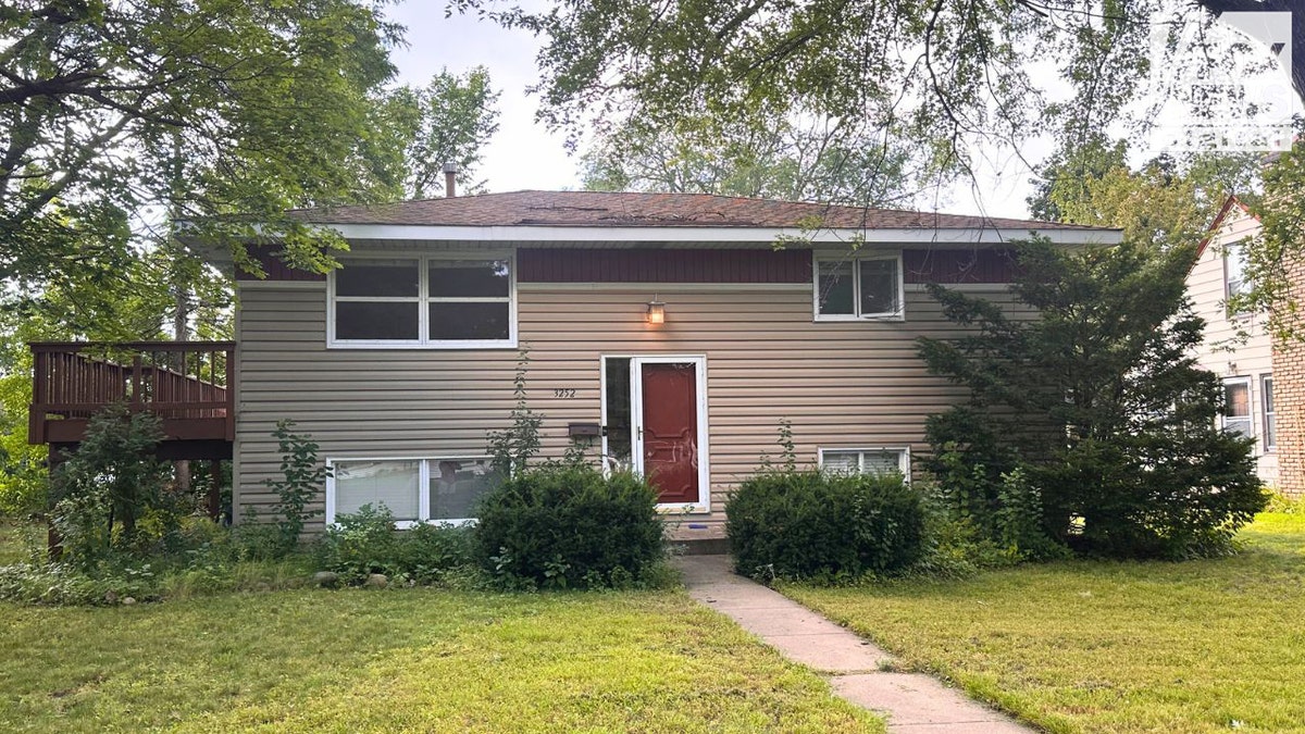 Front exterior of a beige split-level house in St. Louis Park with red front door and small lawn, linked to Robin Westman.