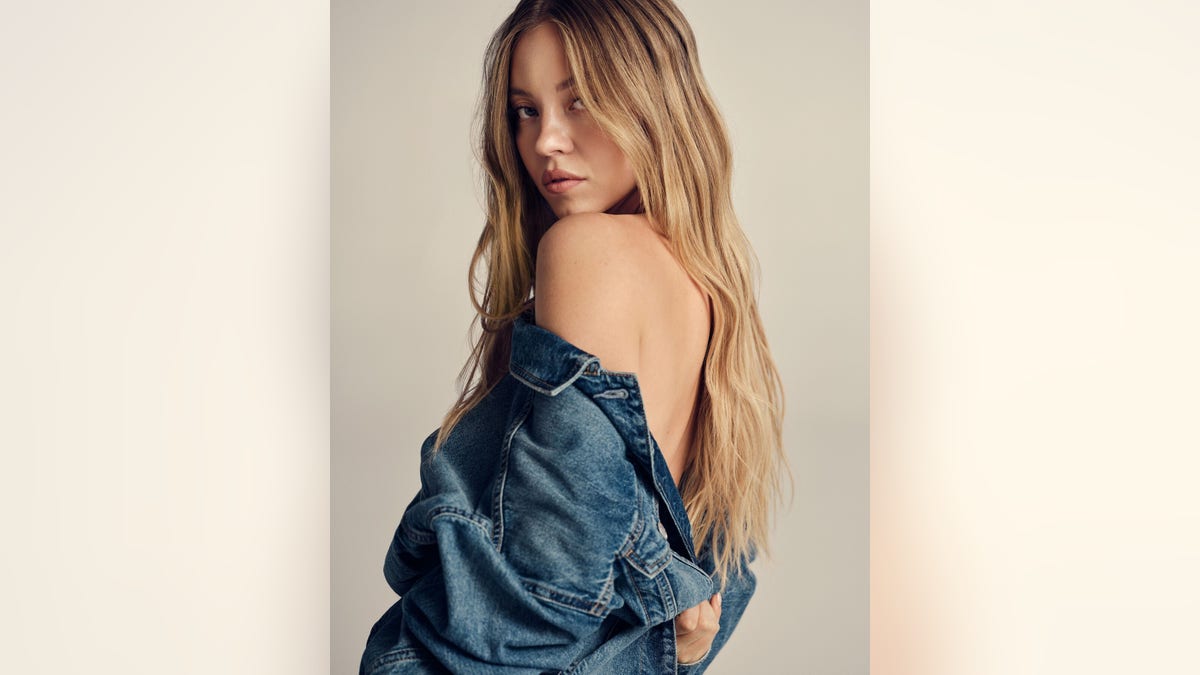 Sydney Sweeney with a pair of jeans slung over her shoulder