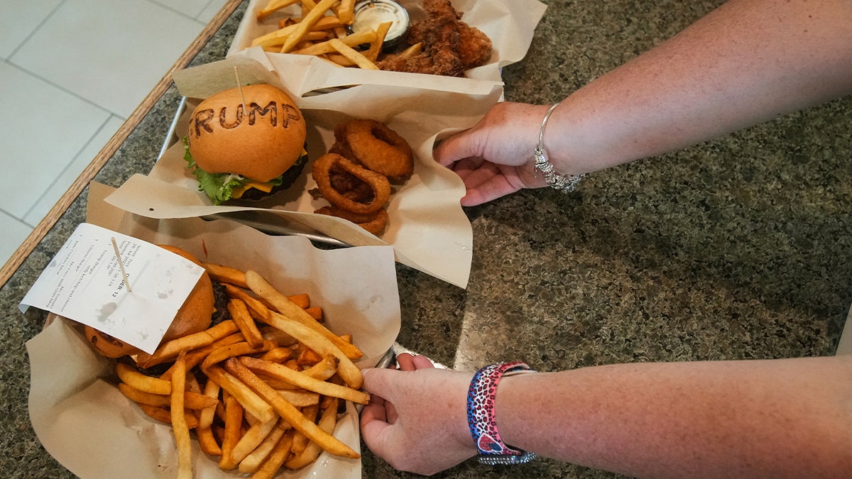 Trump burgers being served from kitchen with "trump" branded on buns