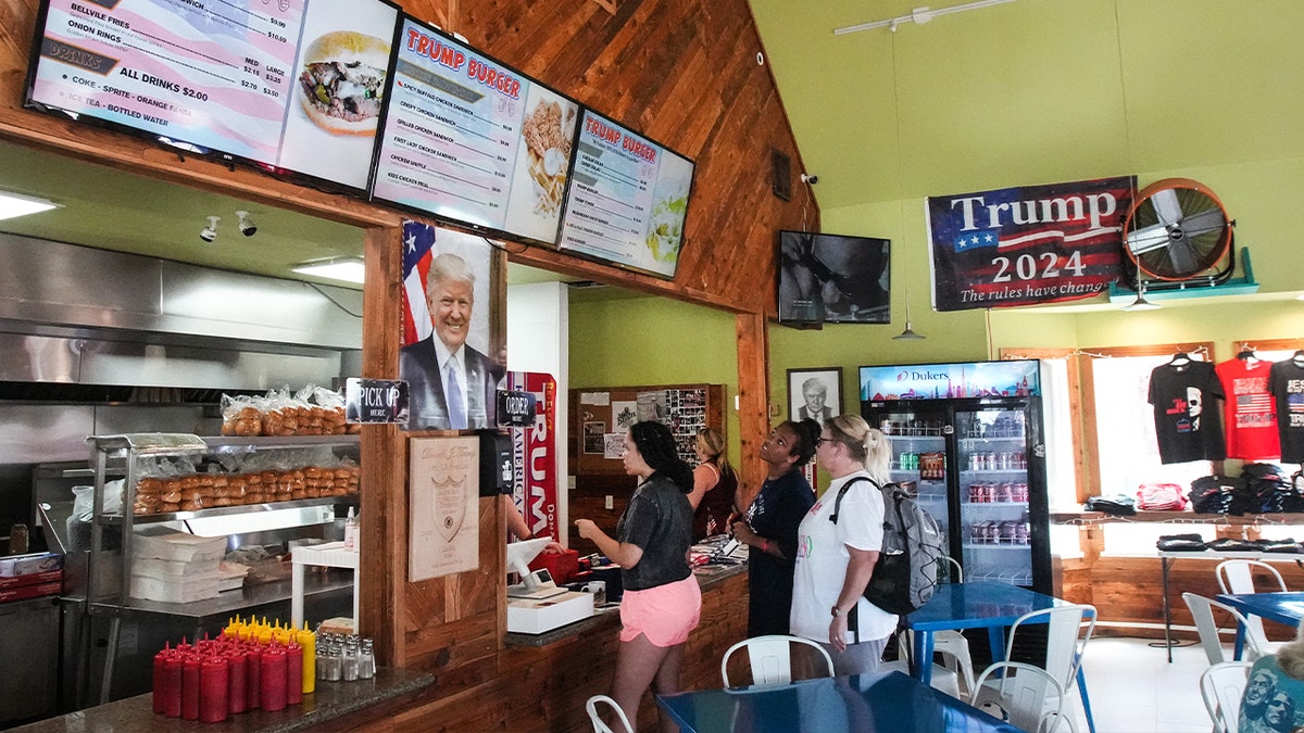 people line up inside to order trump burger at kitchen area