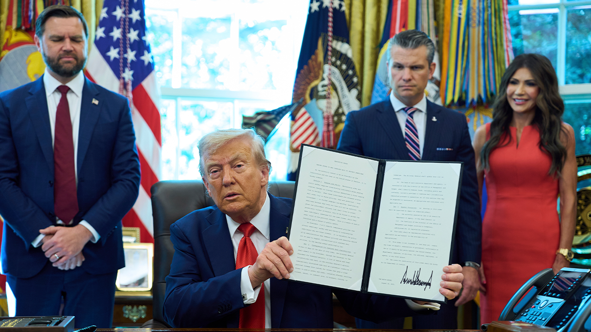 President Trump shows off a freshly signed executive order, with Vice President JD Vance, Defense Secretary Pete Hegseth and DHS Secretary Kristi Noam standing at his sides