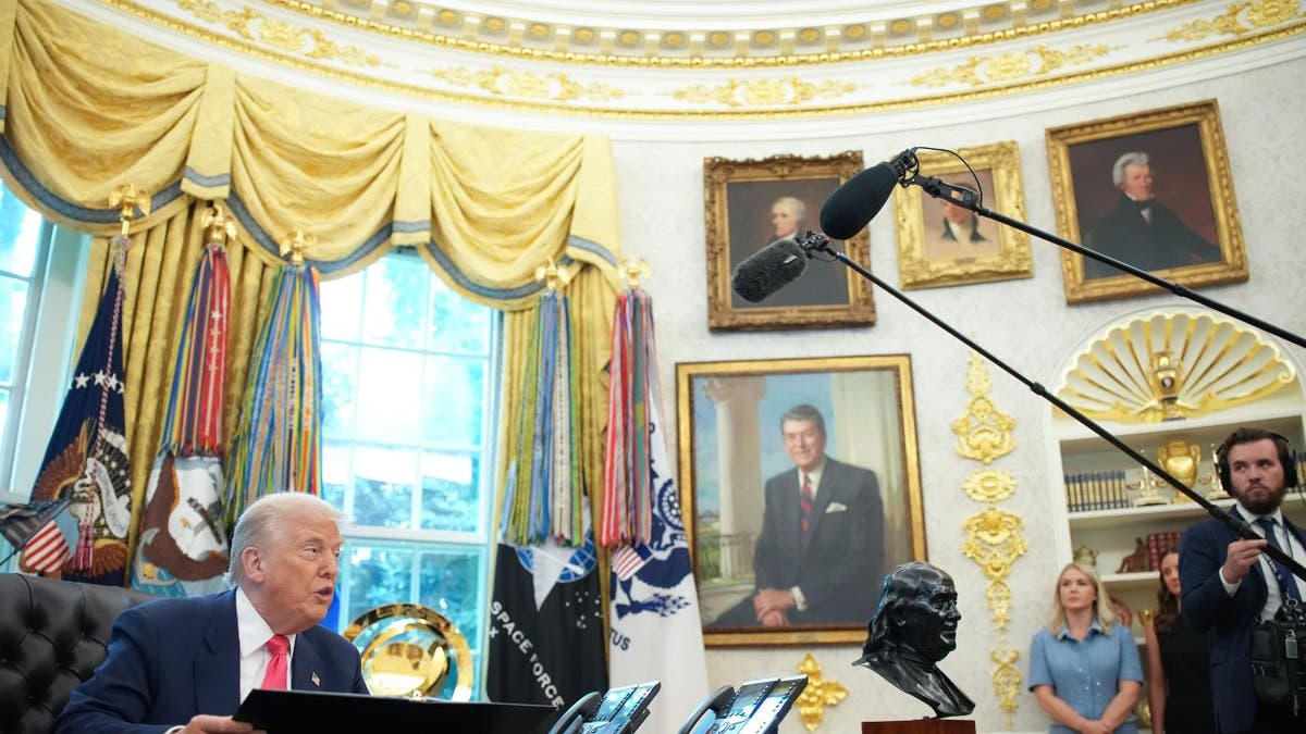 Trump speaks to reporters in the Oval Office with lots of gold details around him