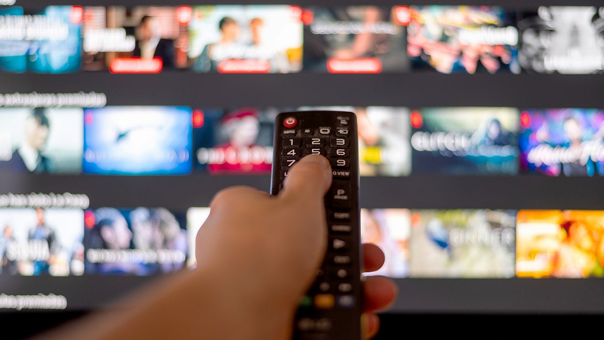 A hand pointing a TV remote.