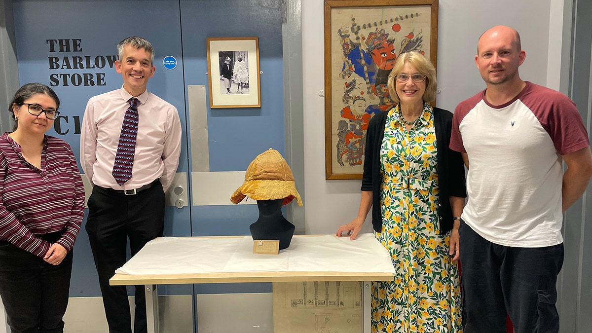Group of curators smiling next to hat