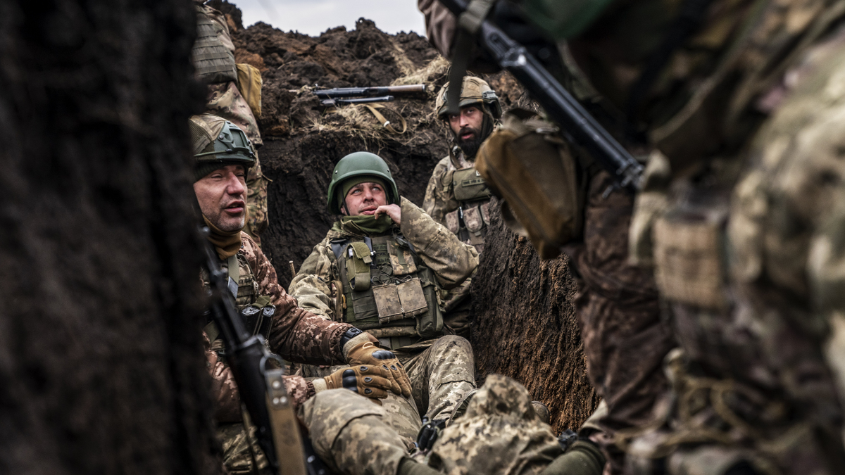 Ukrainian soldiers sit in a trench