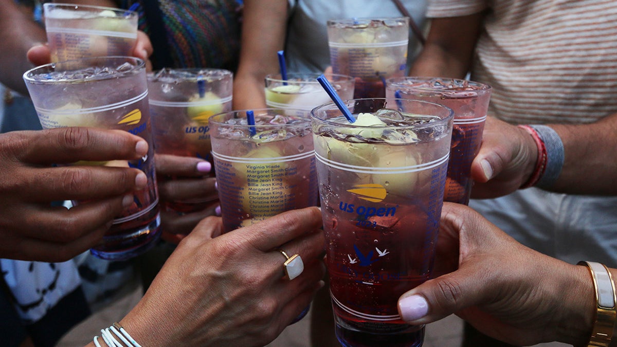 Group of US Open tennis fans toasting Honey Deuce cocktails, seen up close in their hands