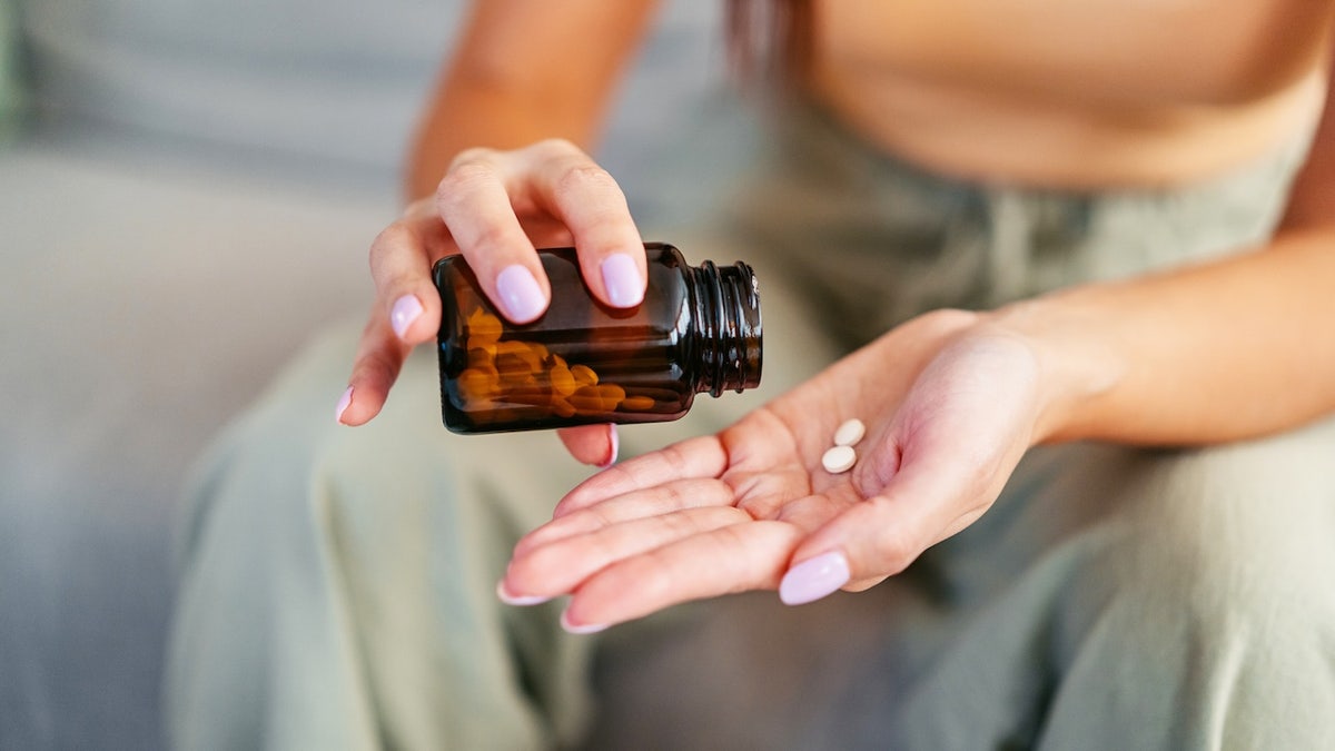 Woman pouring pills by hand