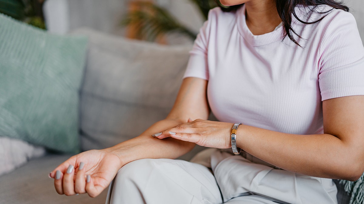 The woman examines the skin on the arm