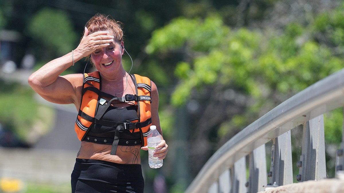 Woman sweating as she walks with weighted vest on, one of the latest workout and fitness trends believed to help weight loss, strength training and bone health.