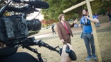 Andrew Callaghan speaks to a man straddling a large wooden cross.