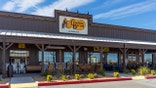 The exterior of a Cracker Barrel Old Country Store with rocking chairs outside is shown.