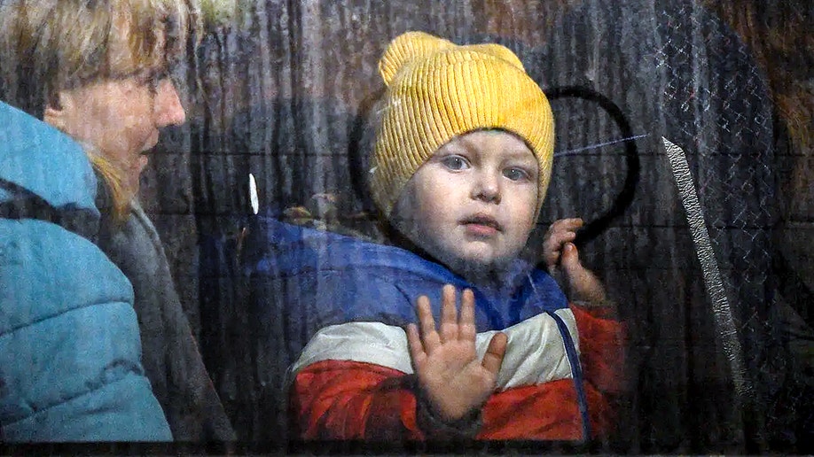 Ukrainian child presses hand against bus window