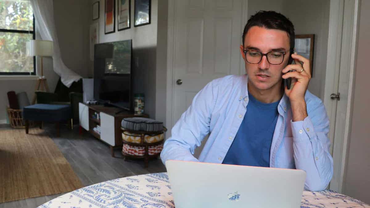 hombre que usa laptop y habla por teléfono mientras está en apartamento