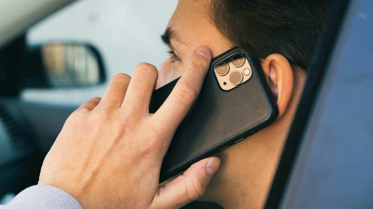Hombre hablando con iPhone de carro negro en el coche