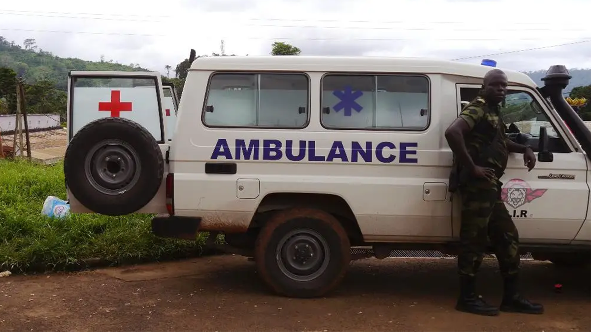 A Cameroon trooper, right, stands next to an ambulance that was used to carry victims of a train that crashed on Friday in Eseka, Cameroon, Saturday, Oct. 22, 2016. Rescue workers dug through the rubble Saturday in search of more injured and dead after a train traveling between two major cities in Cameroon derailed in Eseka, killing scores of people according to rescue workers and hospital staff.