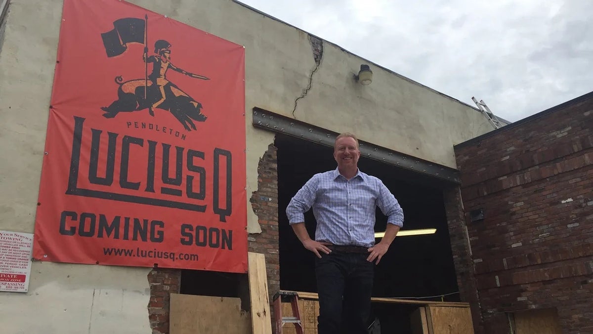Lucius Q co-owner Aaron Sharpe stands outside the building "coming soon" The logo of the restaurant in 2017
