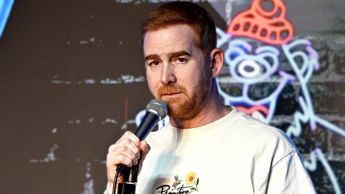 Comedian Andrew Santino holds microphone