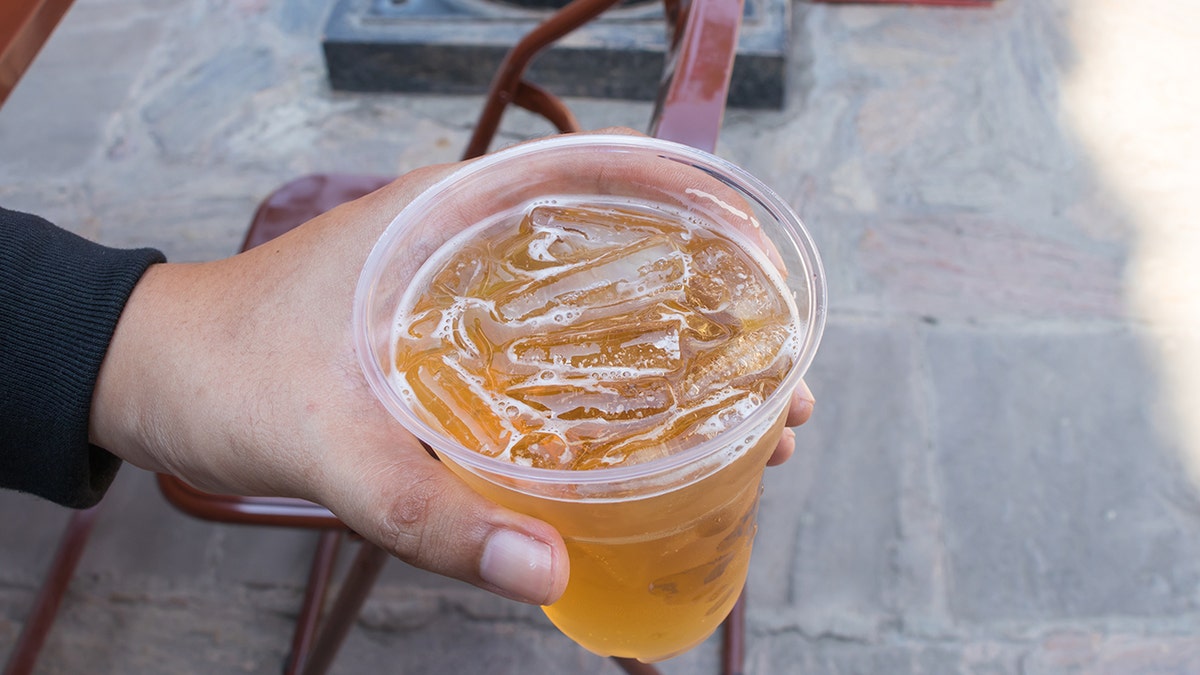 See new social media trends in outdoor restaurant environment with plastic glasses of beer holding ice in outdoor restaurant environment