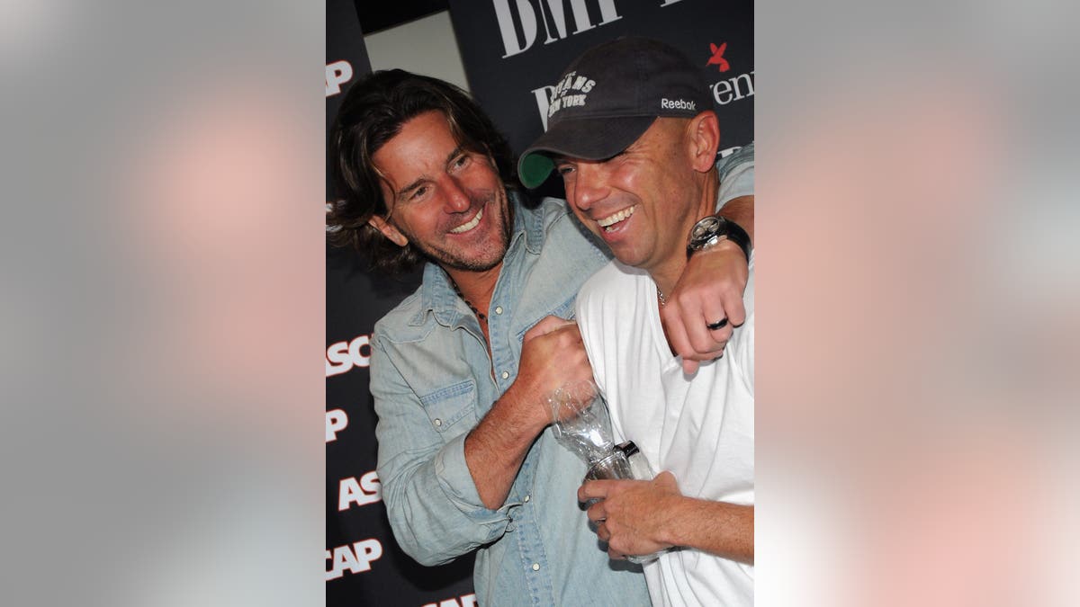 Kenny Chesney and songwriter Brett James share a laugh and hug at an ASCAP event