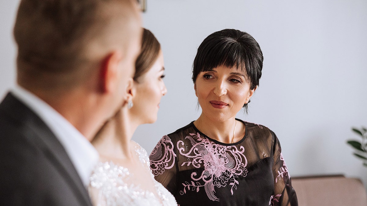 Mother-in-law talking to bride and groom at wedding