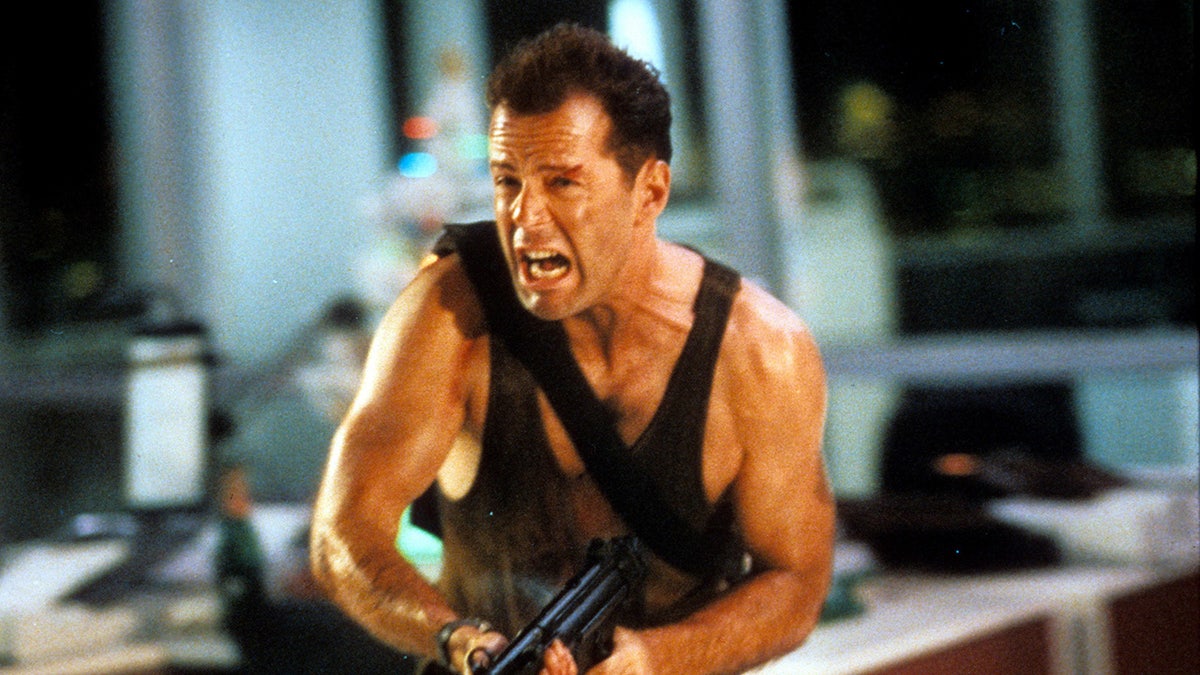 Bruce Willis shooting a gun in a scene from "Die Hard."