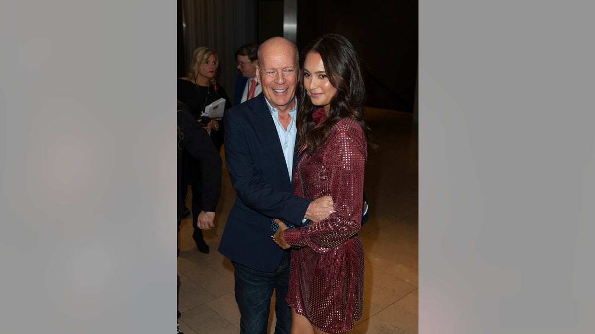 Bruce Willis being embraced by Emma Heming Willis.