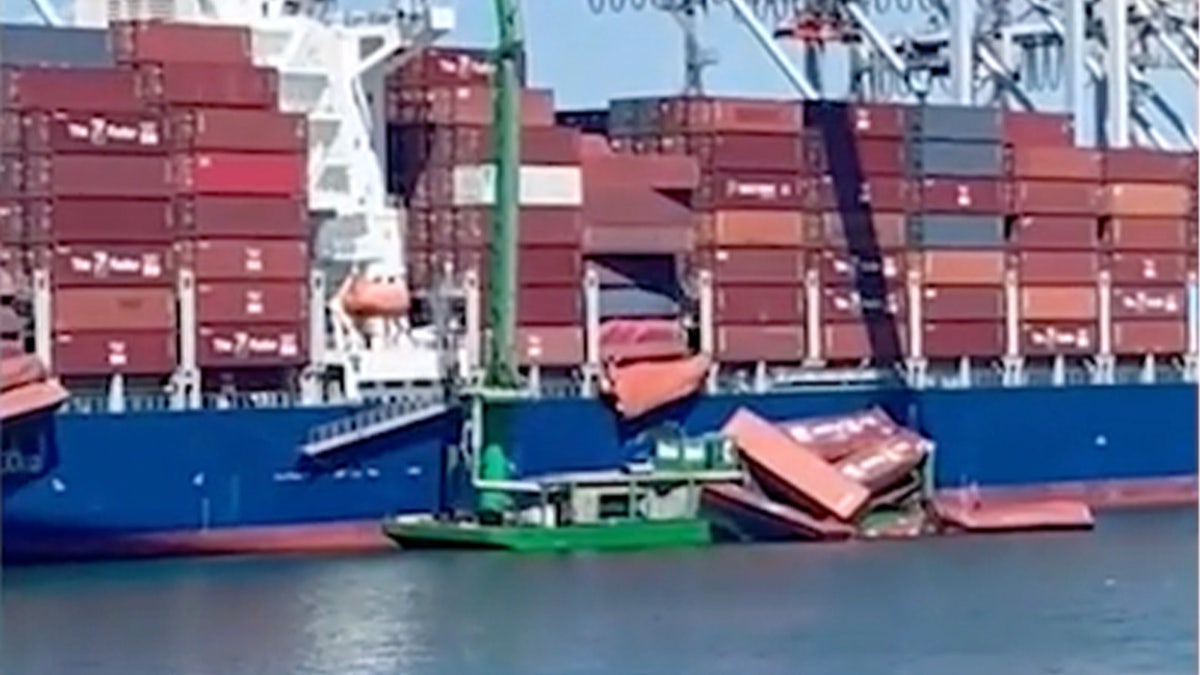 Containers float in water next to ship