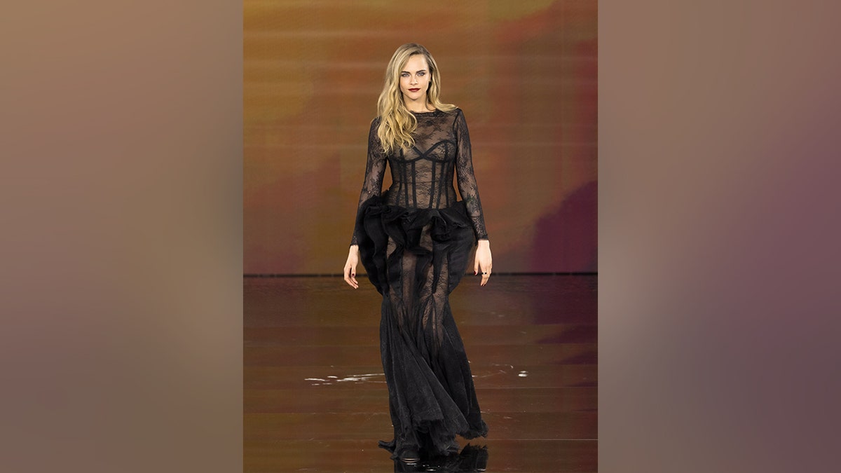 Cara Delevingne walking the runway in a black sheer dress at the L'Oréal Paris Womenswear show in September 2025.